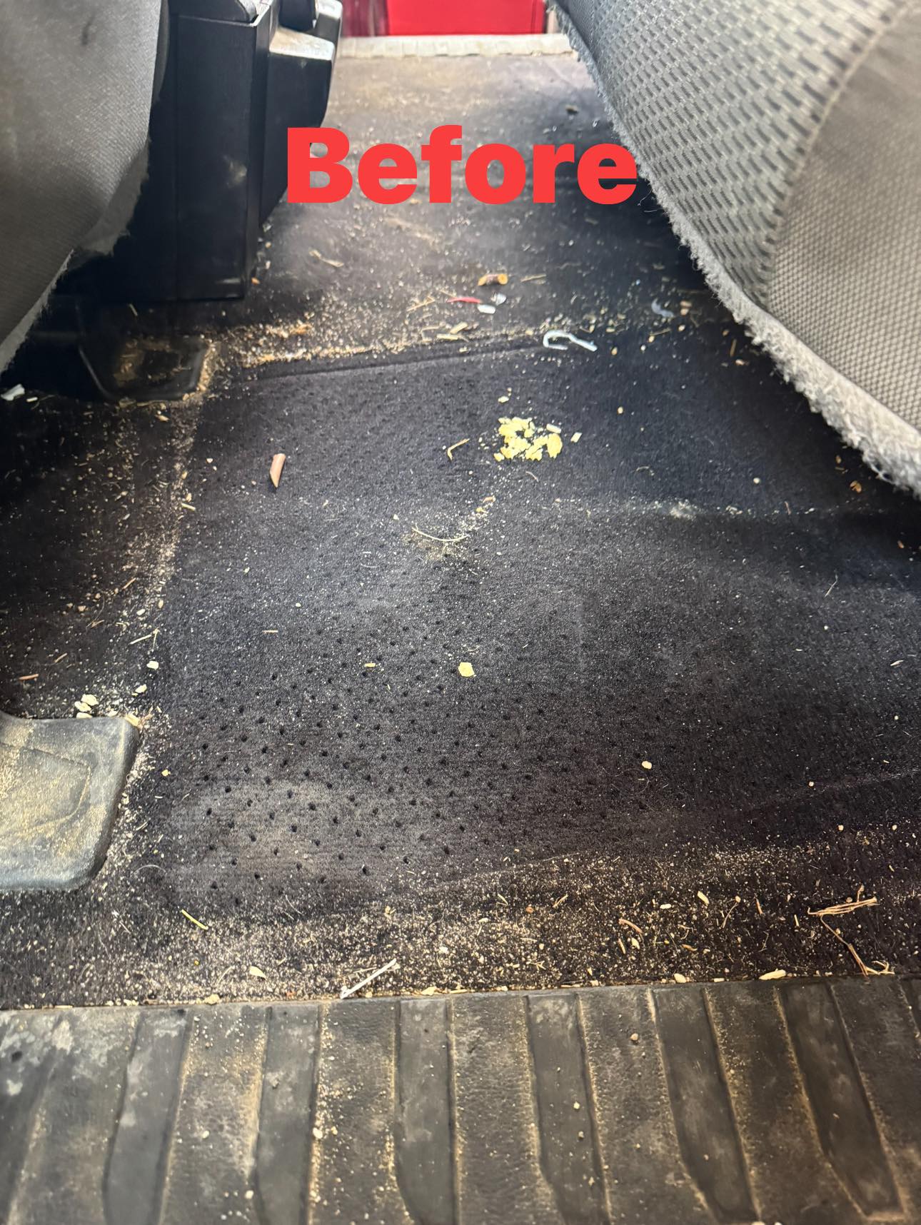 Vehicle rear carpet before detailing with visible dirt and debris.